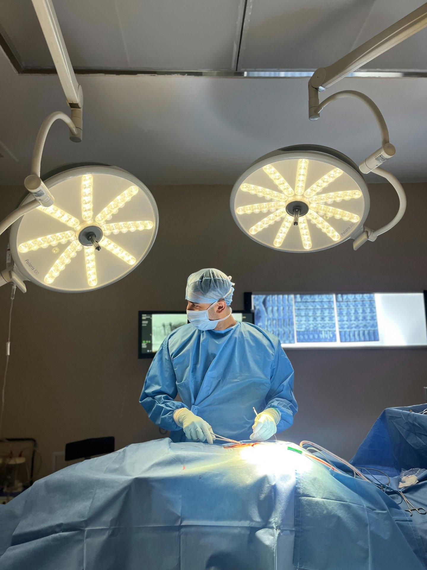 Surgeon performing procedure in operating room under surgical lights